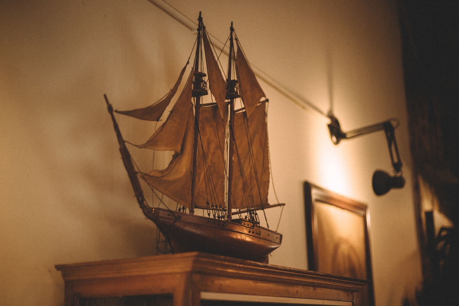 Wooden model galleon lit by a lamp on a mantel, the kind of maritime piece seen at an ocean liner memorabilia auction