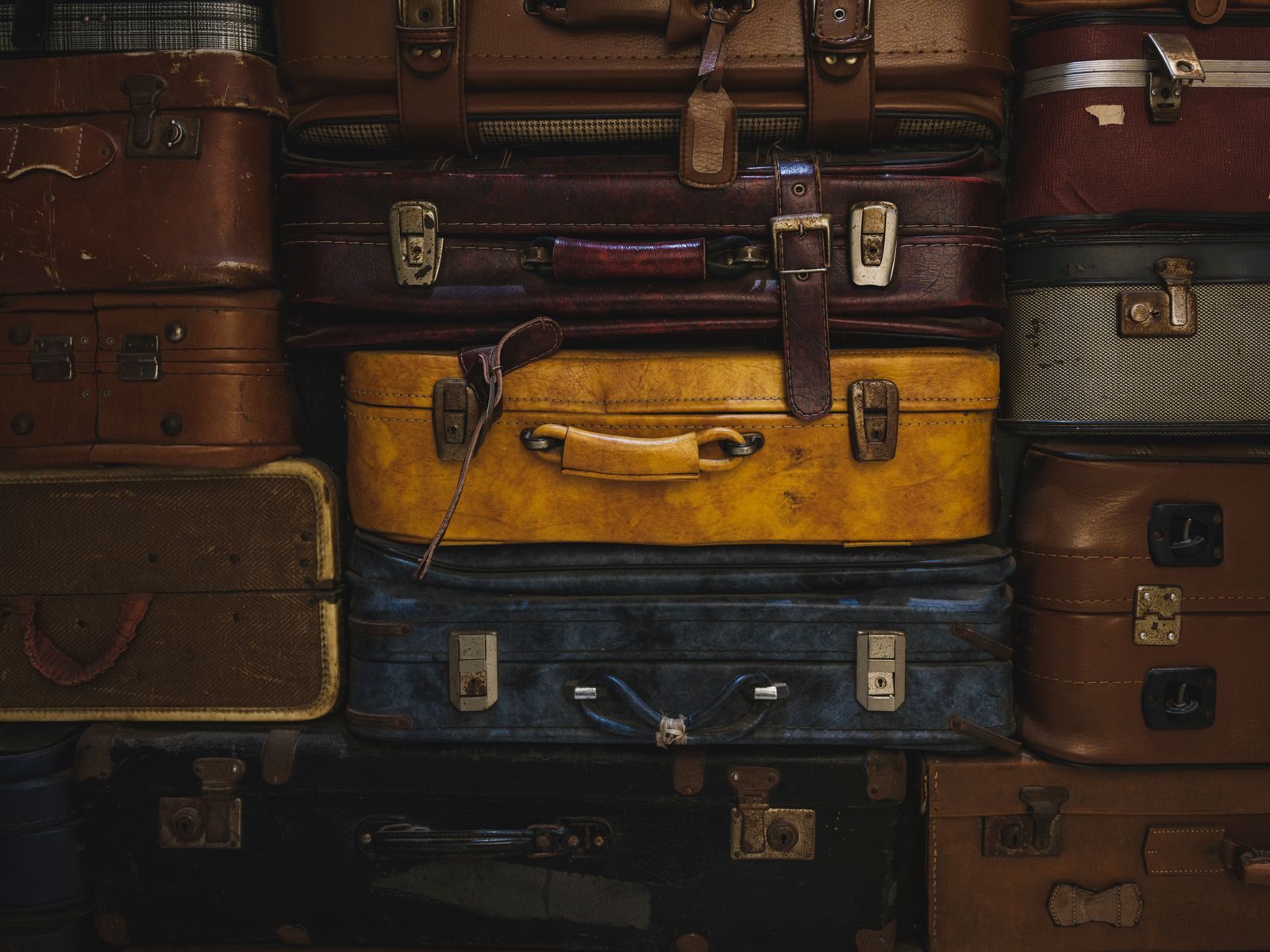 Stack of vintage suitcases in brown, yellow and blue, a secondhand bargain for cruise travelers