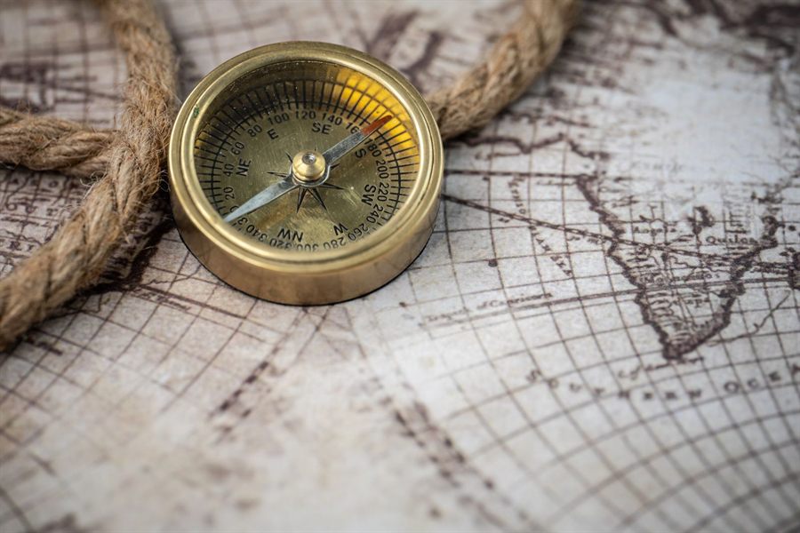 Brass compass resting on an old map beside a coil of rope