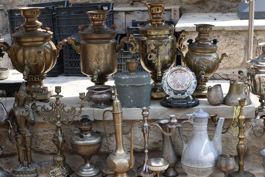 Vintage brass samovars, lamps and antiques displayed at an outdoor market