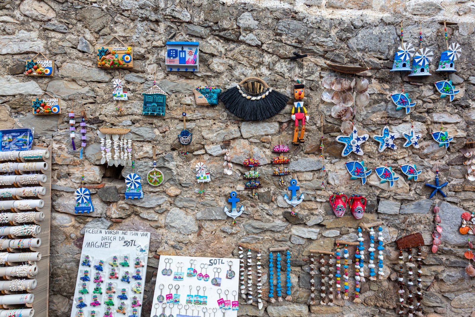 Colorful handmade souvenirs displayed on a stone wall in a port town, typical cruise ship souvenirs from a day ashore